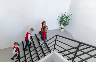 Blick von oben auf Schulkinder in Uniformen, die über eine Schultreppe gehen. - HPIF00190