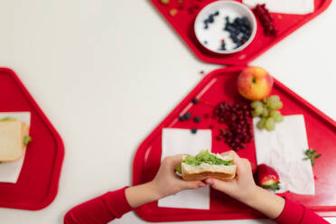 Blick von oben auf ein Schulkind, das in der Schulkantine ein gesundes Mittagessen einnimmt. - HPIF00203