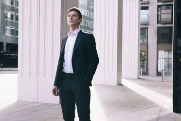 Thoughtful businessman standing in front of columns - AMWF01052