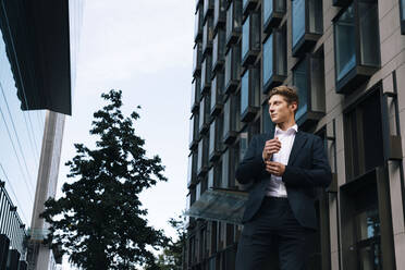 Thoughtful businessman standing in front of building - AMWF01056