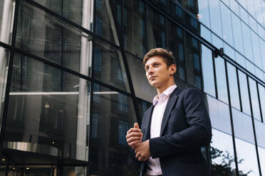 Contemplative businessman standing in front of building - AMWF01057