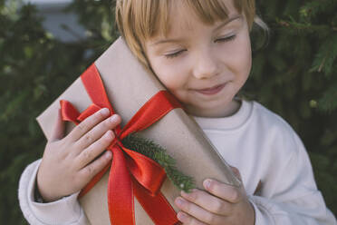 Mädchen mit geschlossenen Augen hält Weihnachtsgeschenkbox - NDEF00232