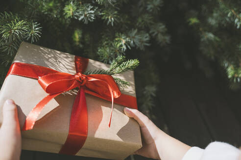 Hand des Mädchens hält Weihnachtsgeschenk-Box mit rotem Band gebunden - NDEF00233