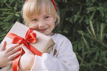 Blondes Mädchen mit Pony hält Weihnachtsgeschenkbox - NDEF00235