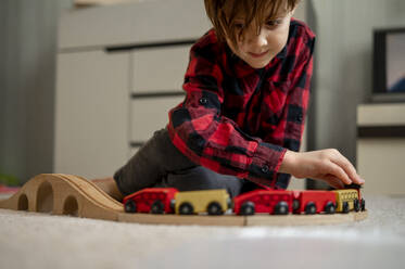 Junge spielt mit hölzernem Spielzeugzug zu Hause - ANAF00585