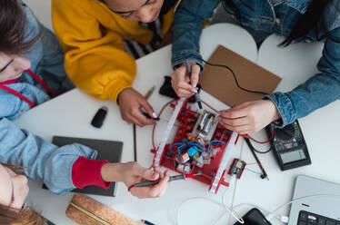 A group of high school students building and programming electric toys and robots at robotics classroom - HPIF00234