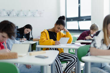 Müde Schüler, die in einer Klasse Notizen schreiben, sitzen an ihren Schreibtischen, das Konzept 