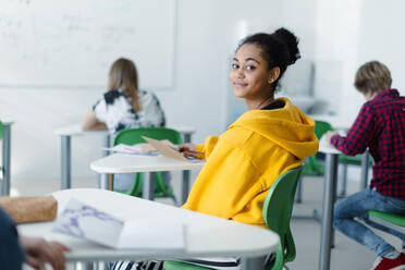 Aufmerksame Schüler in einer Klasse, die an ihren Schreibtischen sitzen und Notizen schreiben, ein Konzept für den Schulanfang, Rückansicht. - HPIF00260