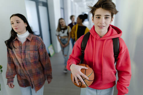 Junge Gymnasiasten, die in einem Korridor in der Schule spazieren gehen, Konzept 