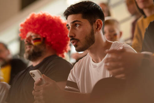 Besorgte Fußballfans, die eine deutsche Nationalmannschaft bei einem Live-Fußballspiel im Stadion unterstützen. - HPIF00325