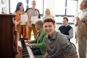 Eine Gruppe von Senioren mit einer jungen Lehrerin singt gemeinsam bei einer Chorprobe. - HPIF00384