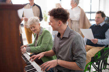 A senior woman with young teacher playing at piano in choir rehearsal. - HPIF00385