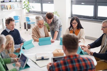 A group of seniors attending IT class in community centre with teacher - HPIF00397