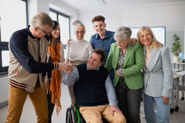 Happy senior students meeting with their friend on wheelchair at university. Social inclusion and university of third age concept. - HPIF00427