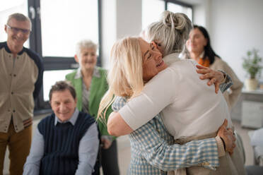 Happy senior women students meeting and hugging in a classroom. - HPIF00437