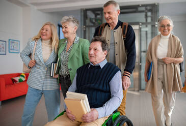 Eine Gruppe glücklicher älterer Studenten, die gemeinsam durch den Korridor der Universität gehen. - HPIF00438