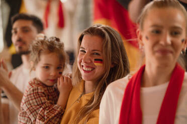 Begeisterte Fußballfans, Mutter mit kleiner Tochter, unterstützen die deutsche Nationalmannschaft bei einem Live-Fußballspiel im Stadion. - HPIF00487
