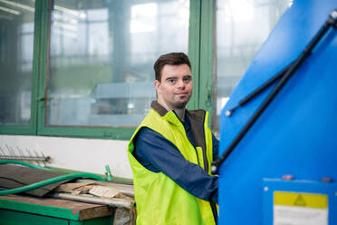 A young man with Down syndrome working in industrial factory, social integration concept. - HPIF00519