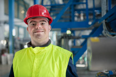 A young man with Down syndrome working in industrial factory, social integration concept. - HPIF00527