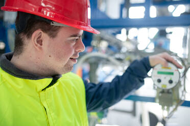 A young man with Down syndrome working in industrial factory, social integration concept. - HPIF00528