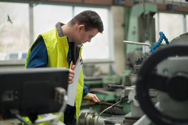 A young man with Down syndrome working in industrial factory, social integration concept. - HPIF00546