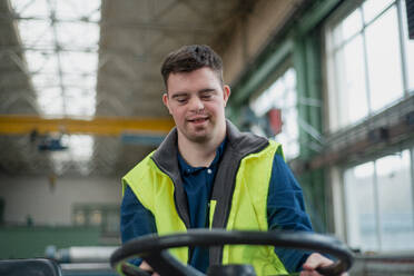 Ein junger Mann mit Down-Syndrom arbeitet in einer Fabrik, Konzept der sozialen Integration. - HPIF00555