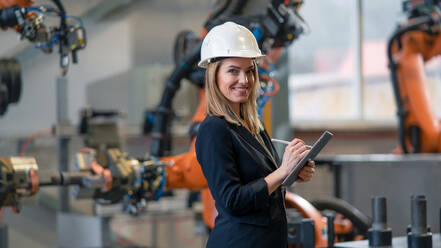 Ein Porträt eines weiblichen Chefingenieurs in einer modernen Industriefabrik, der ein Tablet benutzt. - HPIF00602