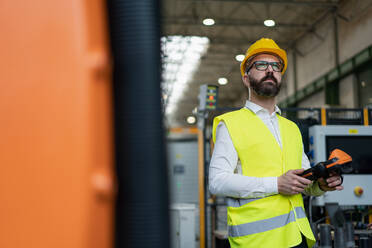 Ein Automatisierungsingenieur hält einen Scanner in einer Fabrik in der Hand. - HPIF00607