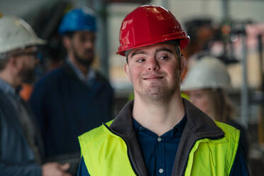 A young man with Down syndrome working in industrial factory, social integration concept. - HPIF00609