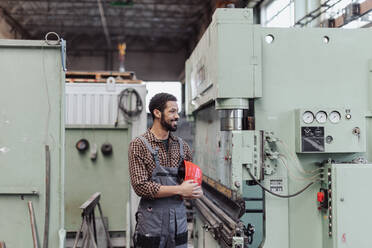 A heavy industry worker with safety headphones and hard hat in industrial factory - HPIF00621