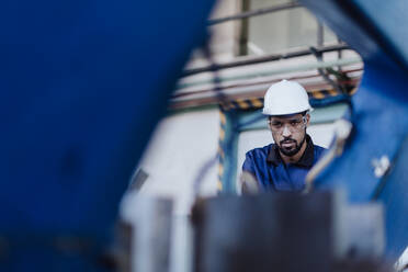 Ein männlicher Fabrikarbeiter in der Pflanzenproduktion bohrt an einer Metallmaschine in einer industriellen Fabrik. - HPIF00626