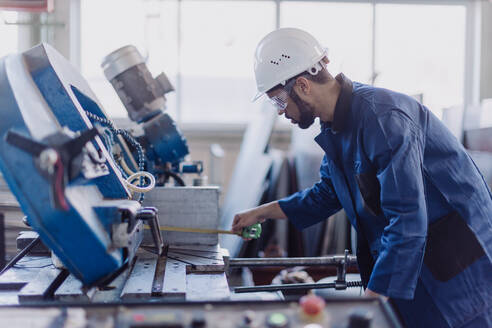 Ein männlicher Fabrikarbeiter in der Pflanzenproduktion bohrt an einer Metallmaschine in einer industriellen Fabrik. - HPIF00627