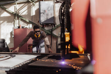 Ein Mann arbeitet an einem Laserschneider für Metall, moderne Technologie in einem metallverarbeitenden Betrieb. - HPIF00634