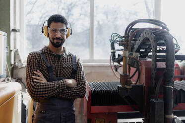 A portrait of heavy industry worker with safety headphones and in industrial factory - HPIF00636