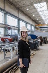 Porträt eines weiblichen Chefingenieurs in einer modernen Industriefabrik, der eine Tafel hält. - HPIF00653
