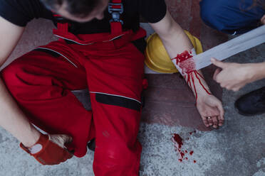 A woman is helping her colleague after accident in factory. First aid support on workplace concept. - HPIF00679