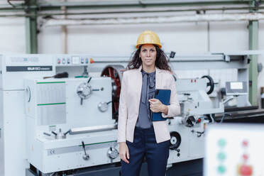 Ein Porträt eines weiblichen Chefingenieurs in einer modernen Industriefabrik, der ein Tablet und eine Maschine benutzt. - HPIF00693