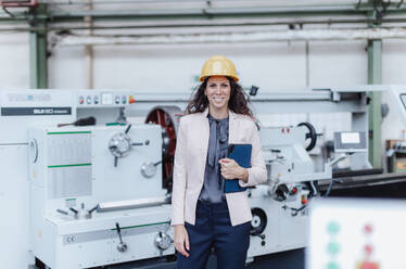 A portrait of female chief engineer in modern industrial factory using tablet and machine. - HPIF00694