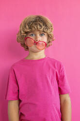 Boy with colored sunglasses against pink background - MEGF00164