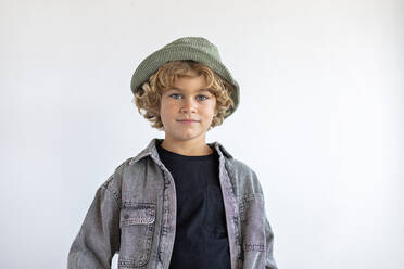 Boy wearing bucket hat and denim shirt against white background - MEGF00176