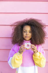 Afro girl with doughnut in front of pink wall - MEGF00189