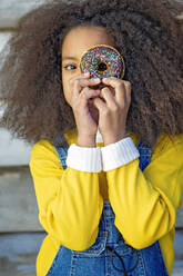 Mädchen schaut durch das Loch eines Doughnuts - MEGF00213