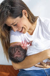 Glückliche Mutter spielt mit neugeborener Tochter zu Hause - MEGF00218