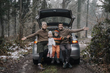 Glückliche Familie, die im Kofferraum eines Autos sitzend Zeit miteinander verbringt - NDEF00239