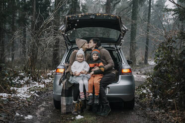 Kuss der Eltern auf den Mund durch Kinder im Kofferraum eines Autos - NDEF00242