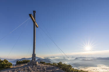 Deutschland, Bayern, Gipfelkreuz des Herzogstands mit aufgehender Sonne im Hintergrund - FOF13189