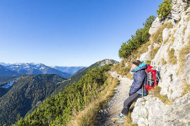 Germany, Bavaria, Female hiker taking break along footpath leading to summit of Heimgarten mountain - FOF13198