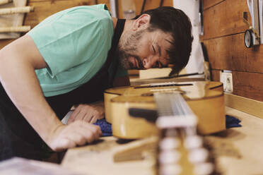 Gitarrenbauer bei der Prüfung der Gitarre in der Werkstatt - JSMF02547