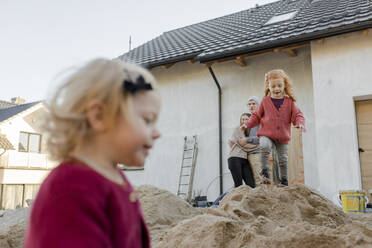 Girl playing on heap of cement with parents at construction site - VIVF00249