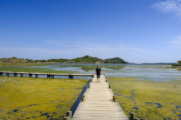 Frankreich, Aude, Peyriac-de-Mer, Männlicher Wanderer auf der Uferpromenade über den See Etang de Peyriac-de-Mer im Sommer - LBF03645